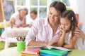 Beautiful little cute girl reading book with mother at the table at home Royalty Free Stock Photo