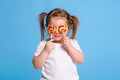 Beautiful little female child holding huge lollipop spiral candy smiling happy isolated on blue background. Royalty Free Stock Photo