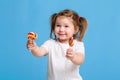 Beautiful little female child holding huge lollipop spiral candy smiling happy isolated on blue background. Royalty Free Stock Photo