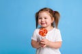 Beautiful little female child holding huge lollipop spiral candy smiling happy isolated on blue background. Royalty Free Stock Photo