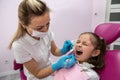 beautiful little female patient grimaces during oral examination by female dentist.