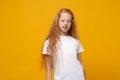 Beautiful little ginger kid girl 12-13 years old wearing white t-shirt isolated on bright yellow wall background