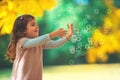 Beautiful little girl playing with yellow leaves and soap bubbles in a autumn park Royalty Free Stock Photo