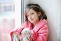 Beautiful little girl in bathrobe near window