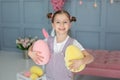 Beautiful little girl with big eyes playing with Easter eggs. Closup portrait smiling Young girl with hairstyle buns. Family holid