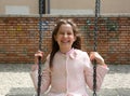 Beautiful little girl with brown hair plays with swing in playgr Royalty Free Stock Photo