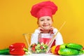 Beautiful little girl chef cook on a yellow background. A child is preparing a vegetable salad Royalty Free Stock Photo