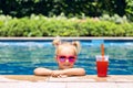 Beautiful little girl, cute toddler with blonde hair in swimwear, sitting at a swimming pool and drinking water melon juice with Royalty Free Stock Photo