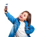 Beautiful little girl is doing selfie using a smart phone, on white background Royalty Free Stock Photo