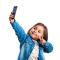 Beautiful little girl is doing selfie using a smart phone, on white background Royalty Free Stock Photo