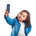 Beautiful little girl is doing selfie using a smart phone, on white background Royalty Free Stock Photo