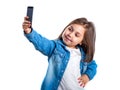 Beautiful little girl is doing selfie using a smart phone, on white background Royalty Free Stock Photo