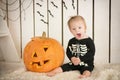 Beautiful little girl with Down syndrome sitting near a pumpkin on Halloween dressed as a skeleton Royalty Free Stock Photo