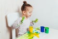 Beautiful little girl draws with finger paints on a white sheet of paper. Royalty Free Stock Photo