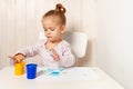 Beautiful little girl draws with finger paints on a white sheet of paper. Royalty Free Stock Photo