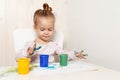 Beautiful little girl draws with finger paints on a white sheet of paper. Royalty Free Stock Photo