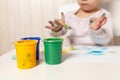 Beautiful little girl draws with finger paints on a white sheet of paper. Creative child development in kindergarten or free time Royalty Free Stock Photo