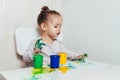 Beautiful little girl draws with finger paints on a white sheet of paper. Royalty Free Stock Photo