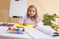 Beautiful little girl draws sitting at table