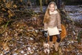 Beautiful sweet little girl dressed in a sheepskin coat and boots sitting on the trunk and in the background Royalty Free Stock Photo