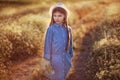 Beautiful little girl enjoing sunset in the field of flowers