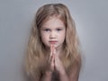 Beautiful little girl folded her hands in a prayerful gesture.