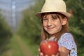 Beautiful Little Girl Giving Red Apple in Sunny Orchard Royalty Free Stock Photo