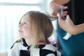 Beautiful little girl hairdresser cuts hair closeup