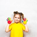 Beautiful little girl with hands in paint smiles in a yellow T-shirt. Children`s creativity. Royalty Free Stock Photo