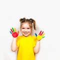 Beautiful little girl with hands in paint smiles in a yellow T-shirt. Children`s creativity. Royalty Free Stock Photo