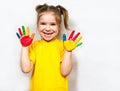 Beautiful little girl with hands in paint smiles in a yellow T-shirt. Children`s creativity. Royalty Free Stock Photo