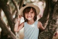 Beautiful little girl in a hat and white dress stands near a tree on a beautiful autumn warm day. Royalty Free Stock Photo