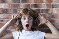 beautiful little girl with headphones at home listening to music and having fun, technology and music concept. Brick background Royalty Free Stock Photo