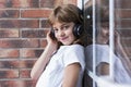 beautiful little girl with headphones at home listening to music and smiling, technology and music concept. Brick background. Royalty Free Stock Photo