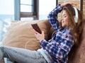 Beautiful little girl in headphones using smartphone on a couch Royalty Free Stock Photo