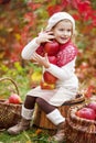 Beautiful little girl holding apples in the autumn garden. . Little girl playing in apple tree orchard. Toddler eating fruits at Royalty Free Stock Photo