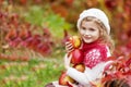 Beautiful little girl holding apples in the autumn garden. . Little girl playing in apple tree orchard. Toddler eating fruits at Royalty Free Stock Photo