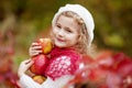 Beautiful little girl holding apples in the autumn garden. . Little girl playing in apple tree orchard. Toddler eating fruits at Royalty Free Stock Photo