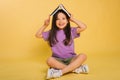 beautiful little girl holding a book on her head while sitting playing while studying. Cute baby teaches lessons on a yellow