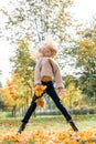 Beautiful little girl jumping with autumn leaves in the park outdoor. leaf fall, lifestyle.