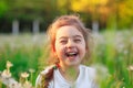 Beautiful little girl  laughing and playing with flowers in sunny spring park. Happy cute kid having fun outdoors at sunset Royalty Free Stock Photo