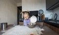 a beautiful little girl is learning to cook in the kitchen. The child spills flour on the kitchen table Royalty Free Stock Photo