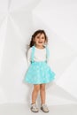 Beautiful little girl with long hair. In a lush short turquoise skirt and white T-shirt.