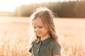 Beautiful little girl with long hair walking through a wheat field on a sunny day. Outdoors portrait. Kids relaxing Royalty Free Stock Photo