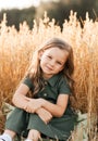 Beautiful little girl with long hair walking through a wheat field on a sunny day. Outdoors portrait. Kids relaxing Royalty Free Stock Photo