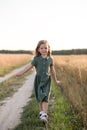 Beautiful little girl with long hair walking through a wheat field on a sunny day. Outdoors portrait. Kids relaxing Royalty Free Stock Photo