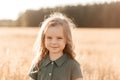 Beautiful little girl with long hair walking through a wheat field on a sunny day. Outdoors portrait. Kids relaxing Royalty Free Stock Photo
