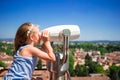 Beautiful little girl looking at coin operated binocular on terrace at small town in Tuscany, Italy