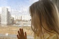 beautiful little girl looks out the window at the rain. stay home