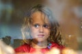 Beautiful little girl looks in the window of a shop in OIA, and makes funny faces Royalty Free Stock Photo